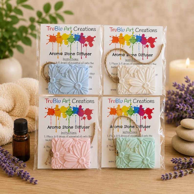 May include: Four square aroma stone diffusers with embossed daisy patterns in light blue, white, pink, and mint green. Each is packaged with a hanging twine cord and a TruBlu Art Creations instruction card featuring a colorful paint splatter logo.