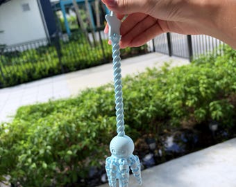 May include: A light blue plastic wand featuring a twisted handle topped with a five-pointed star. The lower section of the wand displays a detailed octopus figure with articulated, dangling tentacles that hang vertically from the central body.