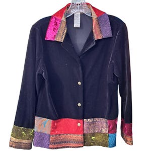 May include: A black velvet jacket with a colorful patchwork trim. The trim features a variety of fabrics, including velvet, brocade, and satin. The jacket has a button closure and long sleeves.
