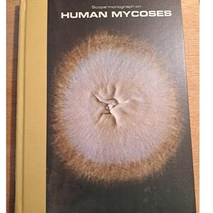 May include: A book titled "Scope monograph on HUMAN MYCOSES" with a brown cover and a close-up image of a light brown and white circular pattern on the front.