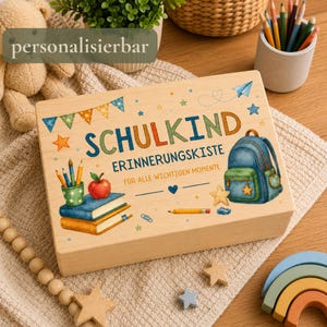 Könnte beinhalten: Eine rechteckige Holzkiste mit einer bunten Illustration eines blauen Rucksacks, einem Bücherstapel, einem Apfel und Stiften. Der Text lautet SCHULKIND ERINNERUNGSKISTE FÜR ALLE WICHTIGEN MOMENTE, ergänzt durch eine Wimpelkette und kleine Sterne.