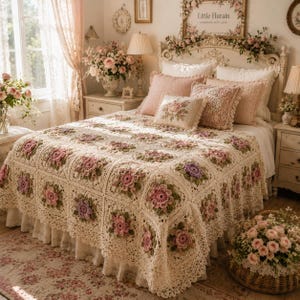 May include: A cream-colored crochet bedspread featuring a repeating square pattern with three-dimensional pink and purple floral motifs and green leaves. The bedspread covers a bed with a ruffled skirt, layered with pink and lace-trimmed pillows.
