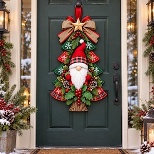 Puede incluir: Un adorno para puerta con forma de árbol de Navidad que presenta un gnomo central con barba blanca y gorro rojo. El árbol está decorado con bayas rojas, piñas, hojas de acebo y un gran lazo de arpillera con una estrella dorada sobre una puerta verde.