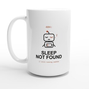 Könnte beinhalten: Ein weißer Keramikbecher mit einer Grafik eines schlafenden Roboters und einem Symbol für schwache Batterie. Über dem Roboter steht der Text 404: und darunter der Text SLEEP NOT FOUND, gefolgt von dem kleineren Text // still running somehow.