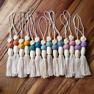 May include: Ten colorful felt ball tassel ornaments with wooden beads and cream-colored tassels. The felt balls are in shades of blue, green, yellow, orange, and purple.