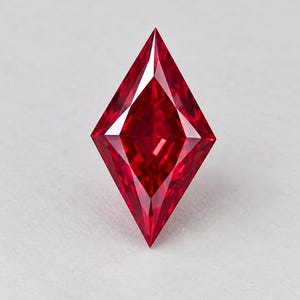 Può includere: Una gemma sciolta a forma di aquilone di un colore rosso profondo e vibrante. La pietra presenta una superficie sfaccettata con bordi geometrici affilati e una punta superiore e inferiore, creando una silhouette simmetrica e allungata.