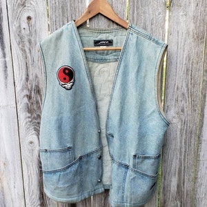 May include: A light blue denim vest with a yin yang patch and the word "Jico" on the back.