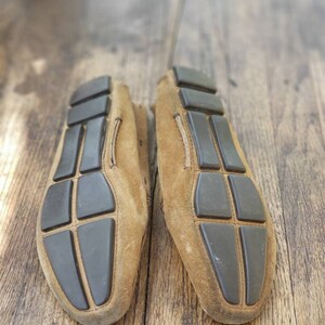 May include: A pair of brown suede loafers with black rubber soles. The soles have a grid pattern.