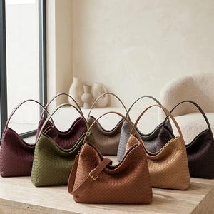 May include: A collection of seven hobo-style handbags featuring a woven texture pattern. The bags are displayed in various colours including burgundy, olive green, tan, beige, grey, and dark brown, each with a single shoulder strap and buckle.