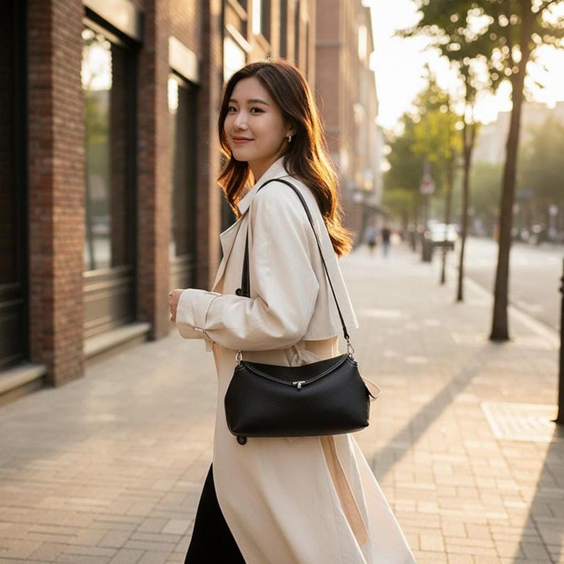 Woman walking city street wearing black pebbled leather shoulder bag, everyday leather purse styled crossbody