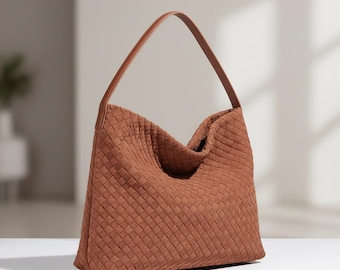 May include: A medium-sized hobo bag in a warm terracotta brown colour. The exterior features a woven basket-weave pattern throughout the body. It includes a single smooth, solid brown leather shoulder strap attached to the top of the bag.