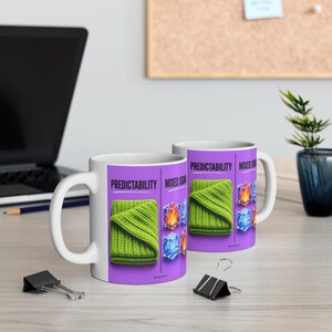 Può includere: Una tazza in ceramica bianca con un design grafico viola diviso in due sezioni etichettate Predictability e Mixed Signals. Il design mostra una coperta in maglia verde piegata accanto a illustrazioni di fuoco e cubetti di ghiaccio.
