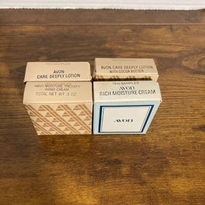 May include: Four vintage Avon skincare sample boxes. The boxes are labeled "Avon Care Deeply Lotion", "Avon Care Deeply Lotion with Cocoa Butter", "Avon Moisture Therapy Hand Cream", and "Avon Rich Moisture Cream". The hand cream box is .5 oz.