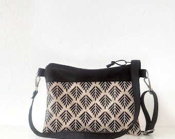 May include: A black and beige crossbody bag with a geometric pattern. The bag has a black adjustable strap and a zipper closure.