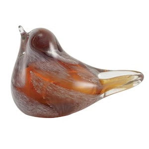 May include: A smooth, stylized glass bird figurine featuring a blend of deep amber, brown, and translucent white swirling patterns. The sculpture has a rounded body, a small pointed beak, and a tapered tail section, all crafted from polished glass.