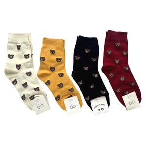 May include: Four pairs of crew socks in cream, mustard yellow, navy blue, and burgundy, each featuring a repeating pattern of small brown bear faces. Each pair includes a white paper tag at the toe area with the text GG Good to Great printed on it.