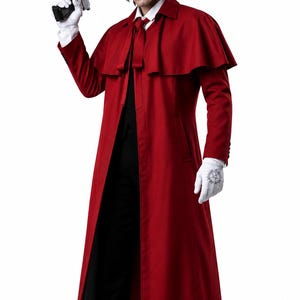 Puede incluir: Un abrigo largo rojo con capa, un sombrero rojo de ala ancha a juego, una camisa blanca de cuello con corbata roja, pantalones negros y guantes blancos. Una mano sostiene una pistola negra grande, mientras el otro guante muestra un emblema circular negro.