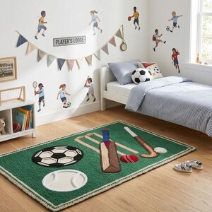 Puede incluir: Una alfombra rectangular verde con un diseño de mechones que representa diversos artículos deportivos, incluyendo un balón de fútbol, un bate de críquet, un palo de hockey, una pelota de béisbol y una pelota de críquet roja, con un borde trenzado.