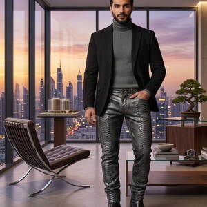 May include: A black blazer worn over a grey ribbed turtleneck sweater paired with metallic silver snakeskin-patterned trousers and black leather boots. The outfit features a structured jacket, a fitted high-neck top, and textured pants.
