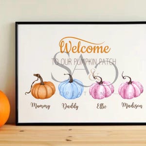 May include: A framed print featuring the text Welcome TO OUR PUMPKIN PATCH with four watercolour pumpkins in orange, blue, light pink, and dark pink. Below each pumpkin are the names Mummy, Daddy, Ellie, and Madison in a brown script font.