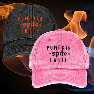 May include: A black acid-wash baseball cap with orange embroidered text reading PUMPKIN spite LATTE and a bright pink acid-wash baseball cap with black embroidered text reading PUMPKIN spite LATTE, both featuring star accents.
