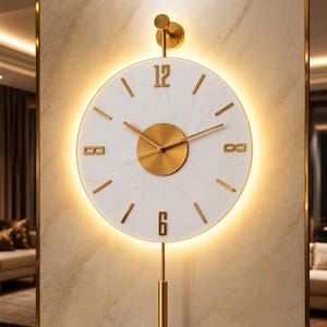Könnte beinhalten: Eine runde Wanduhr mit einem weißen Marmorzifferblatt, goldfarbenen Zeigern und goldfarbenen Ziffern an den Positionen 12 und 6. Die Uhr verfügt über eine goldene Mittelscheibe, eine vertikale goldene Haltestange, ein goldenes Pendel und LED-Hintergrundbeleuchtung.