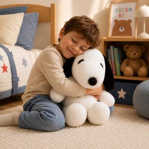 Pode incluir: Um peluche grande de um cão branco com orelhas pretas compridas e nariz preto. O brinquedo de peluche tem uma superfície de tecido macio e texturizado, desenhado com uma cabeça arredondada, focinho proeminente e olhos e boca bordados.