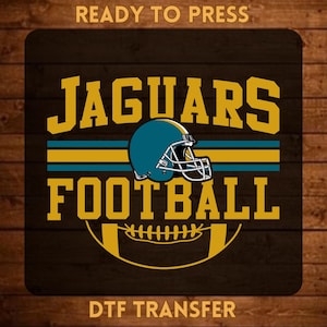 May include: A rectangular DTF transfer sheet featuring the text READY TO PRESS at the top and DTF TRANSFER at the bottom. The center displays the words JAGUARS FOOTBALL in gold, a teal football helmet, and a gold football graphic on a dark background.