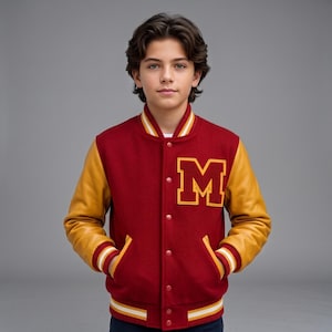 May include: A varsity jacket featuring a deep red wool-blend body and mustard yellow sleeves. The front displays a large, bold letter M in red with a yellow border. It includes a ribbed collar, cuffs, and hem with red, white, and yellow stripes.
