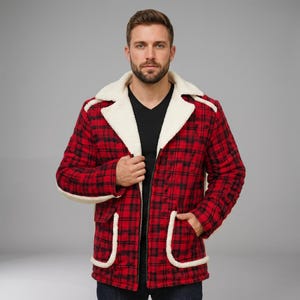 Op de afbeelding: Een rood met zwart geruit jack met een witte sherpa fleece voering, een brede kraag met inkeping en twee grote opgestikte voorzakken met witte sherpa randen. Het jack wordt gedragen over een zwart shirt met V-hals en heeft een ritssluiting.