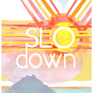 May include: A watercolor painting of a sunset with the words "SLO DOWN" in white text. The painting features a stylized sun with a yellow center and orange and red outer rings. The background is a gradient of pink, orange, and yellow.