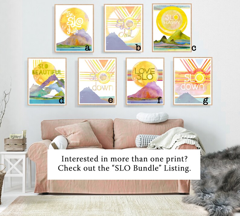 May include: Seven watercolor prints with a mountain and sun design. Each print features a different phrase, including "The Slo Life", "Slo Chill", "Slo Happy", "Slo Beautiful", "Slo Down", "Love Slo", and "Slo Down".