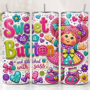 May include: A cylindrical tumbler featuring a colorful graphic print of a doll with pink yarn hair, wearing a patchwork dress and bows. The design includes the text Sweet as a Button and stitched with sass, surrounded by hearts, buttons, and stars.