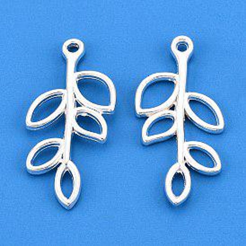 Puede incluir: Dos colgantes de plata con forma de hoja. Cada colgante presenta un tallo con tres hojas caladas. Los abalorios est&aacute;n dise&ntilde;ados para la creaci&oacute;n de joyas, con un peque&ntilde;o lazo en la parte superior.