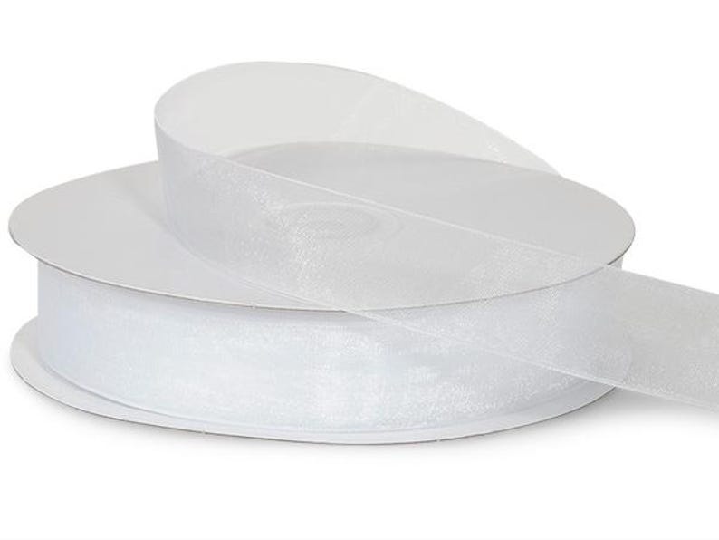 May include: A spool of white sheer ribbon with a shimmery finish. The ribbon is rolled up on a white cardboard spool.