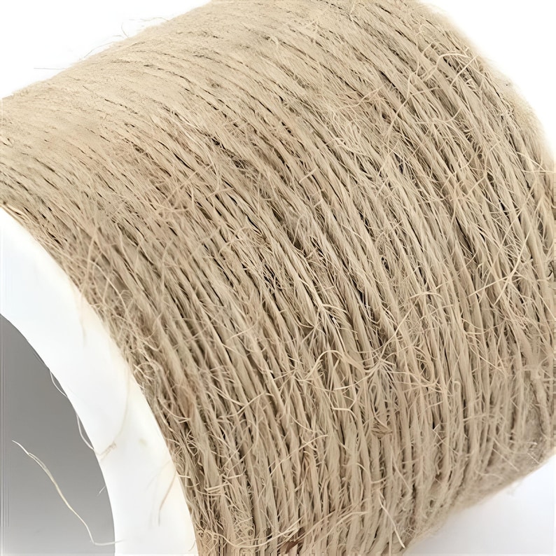 May include: A close-up of a spool of natural twine. The twine is a light beige color and is wound tightly around the spool.