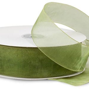 Puede incluir: Un carrete de cinta transparente verde oliva con un n&uacute;cleo de cart&oacute;n blanco. La cinta est&aacute; parcialmente desenrollada, mostrando su textura y color. Ideal para manualidades, envolver regalos y fines decorativos.