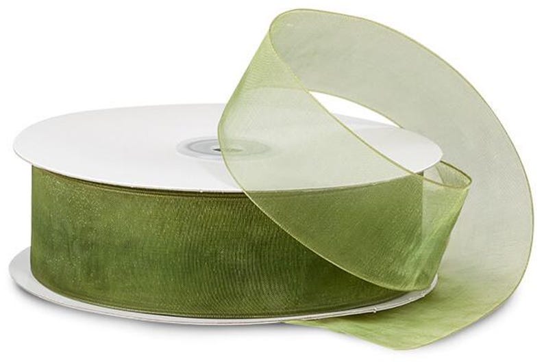 Puede incluir: Un carrete de cinta transparente verde oliva con un n&uacute;cleo de cart&oacute;n blanco. La cinta est&aacute; parcialmente desenrollada, mostrando su textura y color. Ideal para manualidades, envolver regalos y fines decorativos.
