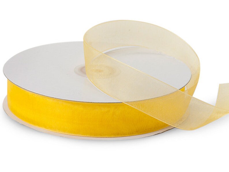 May include: A spool of yellow sheer ribbon. The ribbon is rolled up on a white cardboard core.