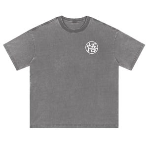 May include: A charcoal grey short-sleeve t-shirt with a crew neckline. The shirt features a white circular graphic on the upper left chest containing the Japanese kanji character for Go, which is enclosed within a white circular outline.
