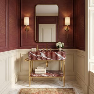 May include: A bathroom vanity featuring a fluted red marble sink basin and a matching lower shelf supported by a gold metal frame. The vanity includes a gold faucet, a rectangular mirror, two wall sconces, and stacked white towels.