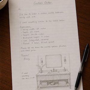 May include: A white sheet of lined paper with the handwritten text Custom Order, detailing a request for a 60-inch wide marble bathroom vanity with an integrated sink, 22-inch depth, and 34-36 inch height, accompanied by a pencil sketch of the vanity.