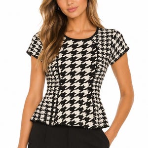 May include: A short-sleeved knit top featuring a black and cream houndstooth pattern. The garment has a round neckline, a fitted bodice with vertical seam detailing, and a flared peplum hem. The edges of the sleeves and neckline are finished with solid black trim.