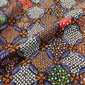 May include: A fabric featuring a repeating geometric pattern of squares and diamond shapes in shades of orange, dark brown, white, purple, and green. The design includes intricate details like cross-hatching, dots, and small heart-like motifs.