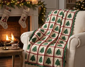 Puede incluir: Una manta de ganchillo con una cuadrícula de cuadrados de color crema, cada uno con un motivo de árbol de Navidad verde. Los cuadrados están unidos por hilo rojo oscuro y la manta tiene un borde festoneado verde, colocada sobre una silla.