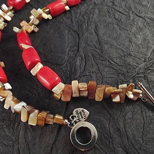 以下が含まれることがあります： 赤と茶色のビーズネックレス。シルバーの留め具と「Made with Love」と書かれたチャームが付いています。