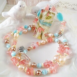 May include: A multi-strand necklace with pink and blue beads, a floral patterned pendant, and a charm that says "Love the World".