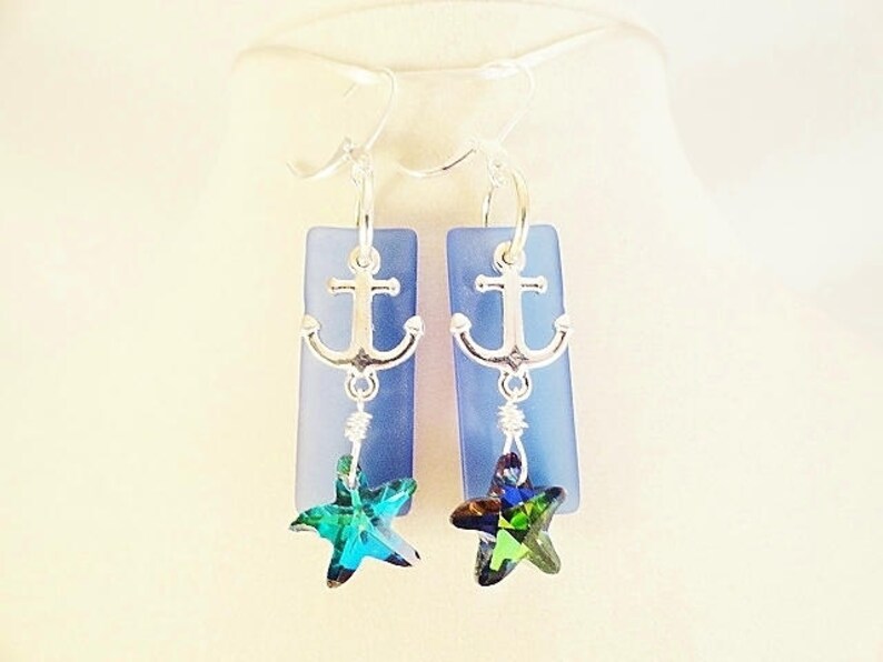 May include: A pair of silver anchor earrings with blue glass and green crystal starfish charms.