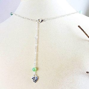 Może przedstawiać: Srebrny naszyjnik z łańcuszkiem, małym zielonym kamieniem i zawieszką w kształcie serca z napisem "Made with Love".