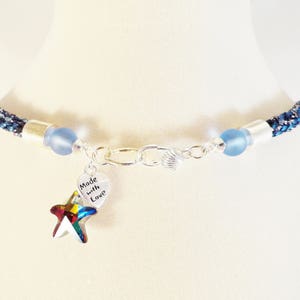 May include: A blue and silver necklace with a charm that says "Made with Love" and a rainbow-colored starfish.
